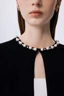 Close-up of black lyocell-wool blend cardigan neckline with large and small pearl embellishments, front detail view