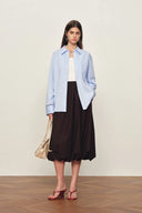 Woman wearing a pale blue cotton shirt with openwork cuffs, front view in relaxed silhouette from Tops collection
