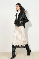 On-model view of ivory satin polka dot skirt with black lace trim paired with black leather jacket and boots