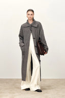 Woman wearing a grey longline cable knit cardigan with a sailor collar and horn buttons