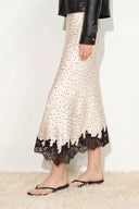 Ivory satin polka dot skirt with black lace trim at asymmetric hem, side view on model.
