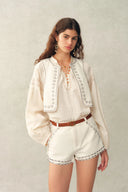 Completo top e shorts in denim di cotone con gilet annodato laterale con nappine e borchie in madreperla stile boho Charlie