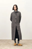 Woman wearing a long grey merino wool blend cardigan with cable knit texture sailor collar and horn buttons