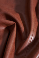 Close-up detail of earth tone eco wax leather fabric showing soft folds and natural grain texture.