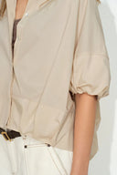 Khaki shirt with bubble puff sleeves, dropped shoulder, and softly curved hem in front view detail.