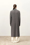 Back view of a grey longline cable knit cardigan with a sailor collar and white trousers