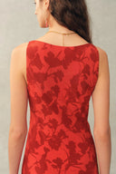 Back view of red floral sleeveless dress in light crinkle gauze with subtle cowl neckline on model