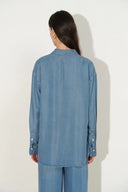 Back view of a sky blue Lyocell denim shirt with long sleeves and buttoned cuffs on model