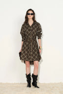 Woman wearing a brown checked flannel shirt dress with a belted waist and long sleeves