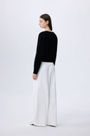 Black lyocell-wool blend knit cardigan with pearl embellishments along the neckline, back view on model