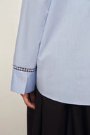 Close-up of light blue cotton shirt cuff with openwork trim and button detail from back view