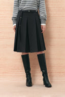 Black belted pleated midi skirt styled with a striped sweater and knee high boots