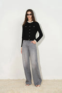 Woman wearing smoke grey crystal embellished straight leg jeans with a black buttoned cardigan