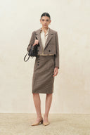 Woman wearing a cropped houndstooth wool blend blazer with structured shoulders and a handbag