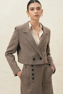 Woman wearing a cropped houndstooth wool blend blazer with structured shoulders and double breasted buttons