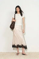 Ivory satin skirt with black polka dots and black lace trim on asymmetric hem, front view on model