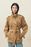 Woman wearing a tan belted faux suede short trench coat with epaulettes and a snap collar