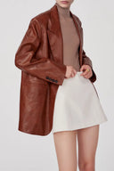 Earth tone eco wax leather blazer with notch lapel and buttoned cuff, front view on model cropped at neck.