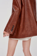 Earth tone eco wax leather blazer sleeve with four black buttons, back side crop view on model.