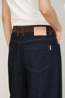Back view of women's dark indigo jeans with a tan faux suede waistband and patch pockets