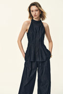 Woman wearing a dark denim halter top and wide-leg pants matching set