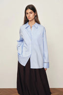 Woman wearing a pale blue cotton relaxed shirt with openwork trim on cuffs, front view on model