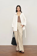 White oversized belted shirt jacket with relaxed collar and long sleeves, front view on model