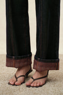 Women's straight leg jeans with plaid fold-up cuffs and contrast topstitching, styled with black sandals
