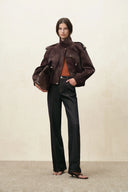 Women's straight leg jeans styled with a brown leather jacket and shoulder bag