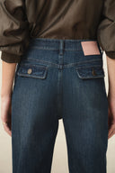 Women's dark wash denim jeans with a high waist and buttoned flap pockets