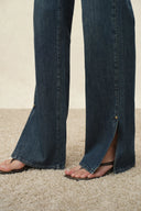 Green washed cotton flare jeans with slit hems styled with sandals
