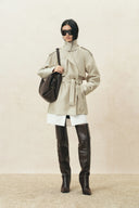 Champagne oversized belted cropped trench coat styled with tall black boots and a black shoulder bag