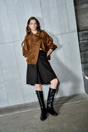 Model wearing a caramel oversized suede jacket with batwing sleeves, black skirt, and knee high boots