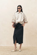Woman wearing an ivory ruched hem lightweight jacket with a black midi skirt and pointed heels