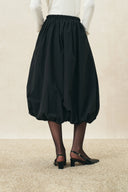 Black elasticated bubble midi skirt with gathered volume and curved hem, styled with black heels