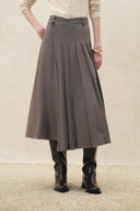Pleated houndstooth midi skirt with a high waist and asymmetric wrap front layered over black boots