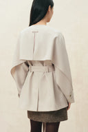 Back view of a cream cropped wool gabardine trench coat with cape sleeves and belt