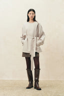 Woman wearing a belted wool gabardine cropped trench coat with balloon sleeves and tall boots