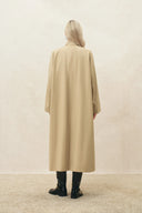 Back view of a beige wool blend long coat styled with black boots for women's outerwear
