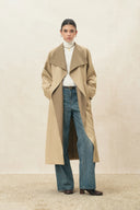 Model wearing a beige wool blend trench coat with a white turtleneck and wide leg jeans