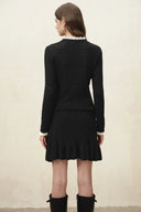 Back view of a black wool blend cardigan with openwork knit detailing and a scalloped hem