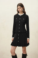 Black wool blend cardigan with pearl buttons, scalloped hem, and white ruffled collar and cuffs on a model