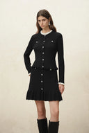 Black knit cardigan with button front, scalloped trim and ruffled hem styled with a matching skirt