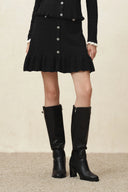 Black knit skirt with button front and layered ruffled hem, styled with knee high boots