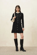 Black knit skirt with front buttons and a scalloped ruffled hem, styled with tall boots