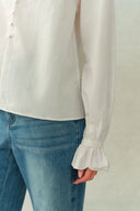 White crinkle cotton blouse with gathered ruffle cuffs and long sleeves, paired with blue jeans