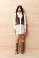 White oversized shirt dress styled with a brown embroidered vest and knee high brown boots