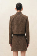 Back view of a woman wearing a brown wool blend jacket with tailored seams and curved sleeves