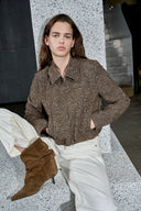 Woman wearing a brown flecked wool blend jacket with curved sleeves and a hidden zip, styled with white pants