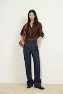 Woman wearing high waisted wide leg dark denim jeans with a brown shirt and shoulder bag